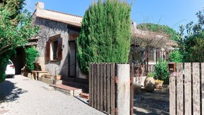 Une maison de campagne à l’aspect rustique, avec une façade en pierre, un portail en bois et une voiture garée devant.
