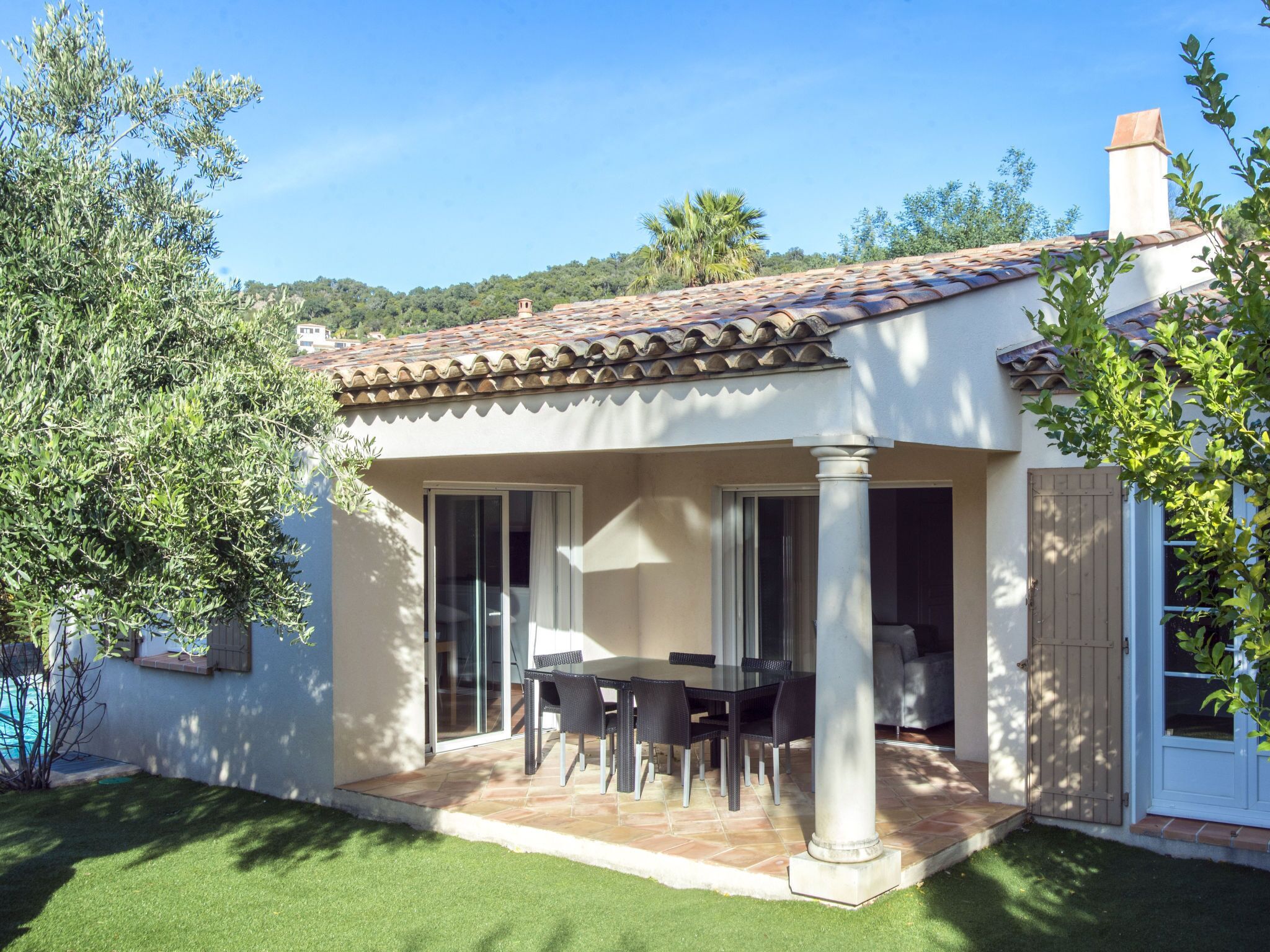A house with a patio, a table with chairs, and a view of the surrounding landscape.