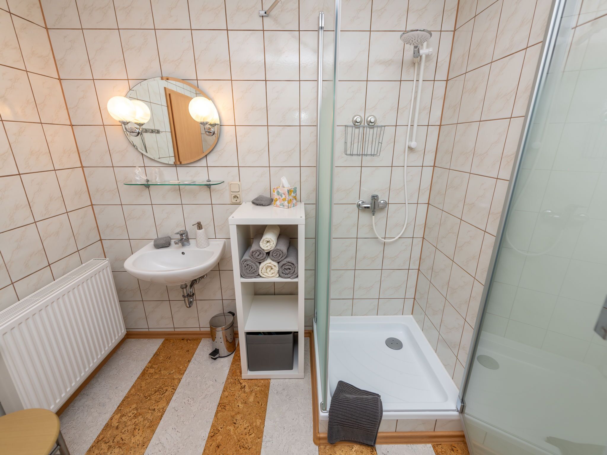 A modern bathroom with a glass-enclosed shower, a white sink, and a mirror with lights.