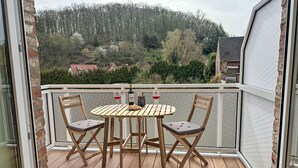 A wooden deck with a table and chairs, overlooking a forested hillside. - An der Eine by Interhome (Stangerode)
