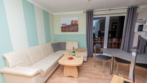 A modern living room with a beige sofa, a wooden coffee table, and a dining area with a small table and chairs. - An der Eine by Interhome (Stangerode)
