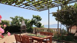 An outdoor patio with a wooden table and chairs, a barbecue grill, and a view of the sea. - Valentina by Interhome (Novi Vinodolski)