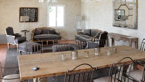 Un vaste salon doté d’une table à manger en bois, de canapés en cuir et d’un lustre.