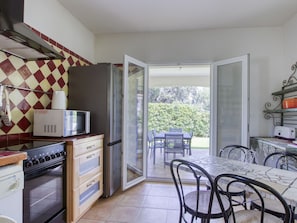 Enjoy meals in the kitchen, then dine at the adjacent table, and step out to a balcony with a garden view.