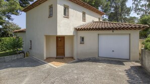 Une maison à deux étages, avec un toit en tuiles, un garage et une allée gravillonnée.