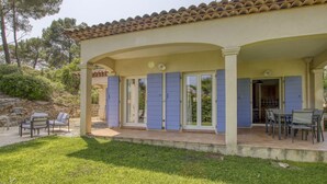 Une maison avec un toit en tuiles, un patio couvert et une pelouse verdoyante.