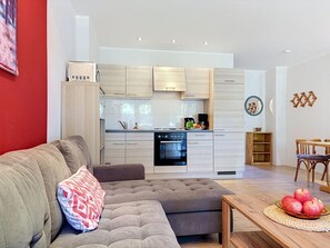 A modern living room with a grey sofa and a dining area with a wooden table and chairs. - Lenzer Höh by Interhome (Plau am See)