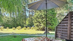 An outdoor patio with a table covered in a floral tablecloth, a glass of water, and a bowl of fruit. - Lenzer Höh by Interhome (Plau am See)