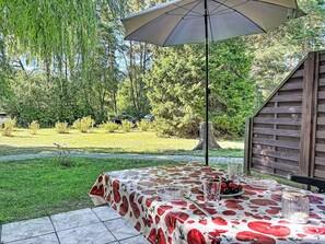 An outdoor patio with a table covered in a floral tablecloth, a glass of water, and a bowl of fruit. - Lenzer Höh by Interhome (Plau am See)