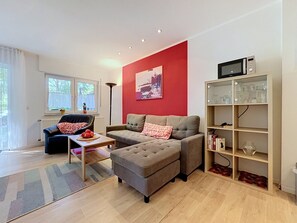 A modern living room with a sofa, ottoman, and a coffee table. There is a bookshelf with books and decorative items. - Lenzer Höh by Interhome (Plau am See)