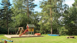 A playground with swings, a slide, and a small house structure. - Lenzer Höh by Interhome (Plau am See)