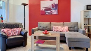 A modern living room with a red accent wall, a black leather sofa, a grey sectional, and a coffee table with apples. - Lenzer Höh by Interhome (Plau am See)
