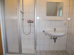 Une salle de bain avec une douche à parois de verre, un lavabo blanc et un miroir au-dessus du lavabo.