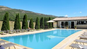 Une piscine avec des chaises longues et un bâtiment doté d’un toit en tuiles.