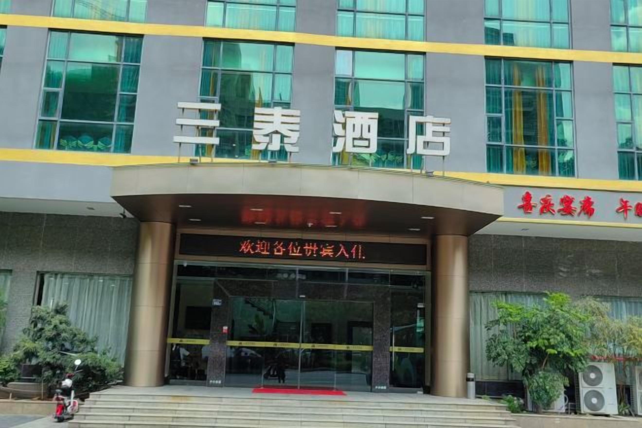 A hotel entrance with a large sign and a red carpet leading up to the door.