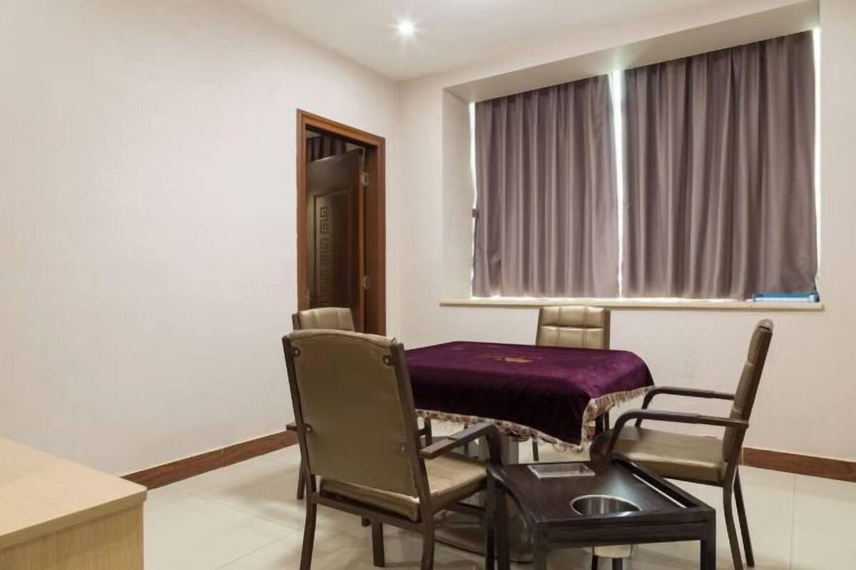 Ein Zimmer mit Esstisch, vier Stühlen, einem Fenster mit Vorhängen und einer Tür.