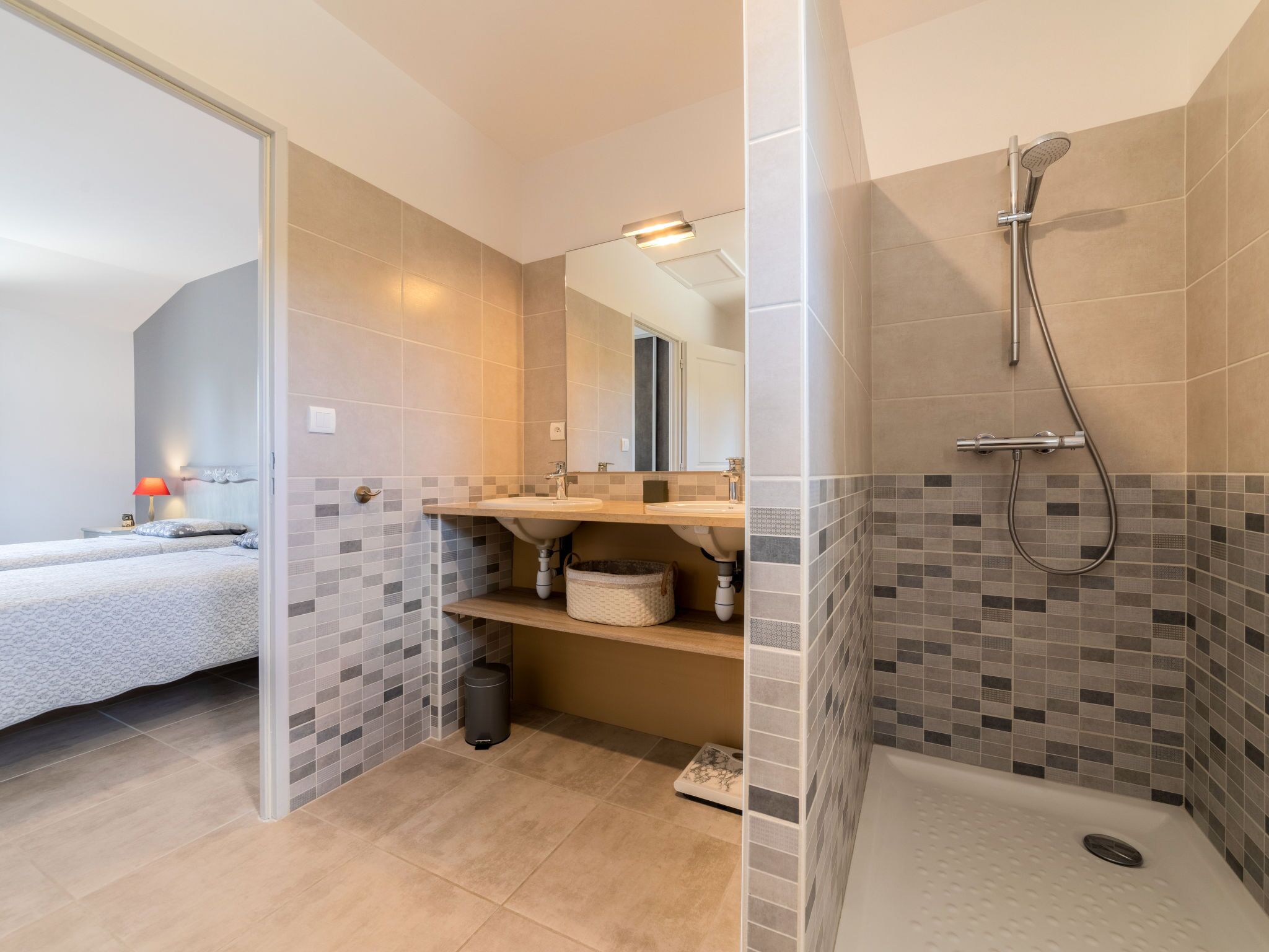 A modern bathroom with a shower, a sink, and a mirror.