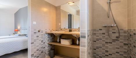 A modern bathroom with a shower, a sink, and a mirror.