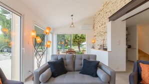 Ein modernes Wohnzimmer mit grauem Sofa, zwei Sesseln und einem Essbereich mit Tisch und Stühlen.