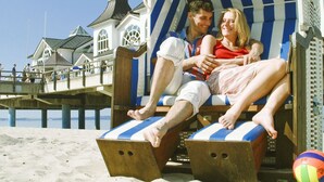 A couple relaxing on a beach chair with a view of a pier and buildings in the background. - Seepark Sellin by Interhome (Ostseebad Sellin)