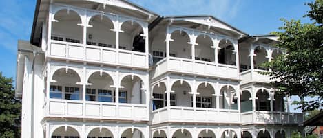 Un immeuble à plusieurs étages doté d’une façade symétrique, avec des fenêtres en arc de cercle et des balcons à chaque étage.