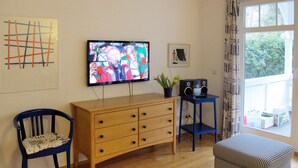 A living room with a television, wooden furniture, a potted plant, and a window with curtains. - Juliusruh by Interhome (Juliusruh)