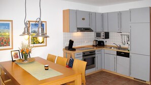 A modern kitchen with grey cabinets, a stainless steel oven, a microwave, and a dishwasher. There is a dining table with chairs and a vase of flowers. - Kap Arkona by Interhome (Breege)
