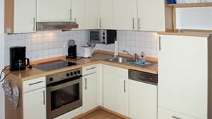 Una cocina compacta con armarios blancos, estufa, horno, microondas y lavavajillas.