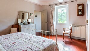 Une chambre à coucher avec un lit, une commode et une fenêtre donnant sur des arbres.