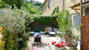 Une terrasse aménagée avec du mobilier d’extérieur, une table et des plantes en pot.