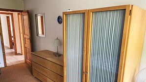 A room with a wooden dresser, a mirror, a lamp, and a sliding door with curtains. - Apartment Carola by Interhome (Godern)