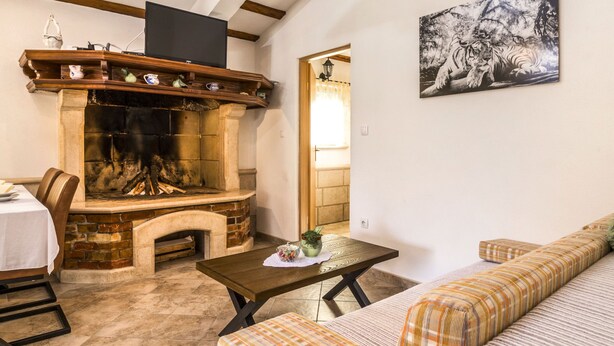 Ein gemütliches Wohnzimmer mit Kamin, einer Couch, einem Tisch und einem Bild an der Wand.