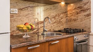 Eine Küche mit Granitarbeitsplatten, einer Edelstahl-Spüle, einem Gasherd und Holzschränken.