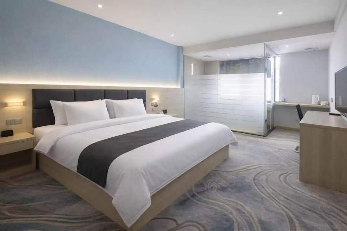 Une chambre d’hôtel avec un grand lit, des tables de chevet, un bureau et un téléviseur.