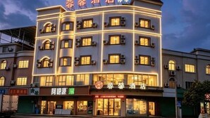 Ein mehrstöckiges Hotel mit beleuchteter Beschilderung, mehreren Balkonen und einem Geschäft im Erdgeschoss.