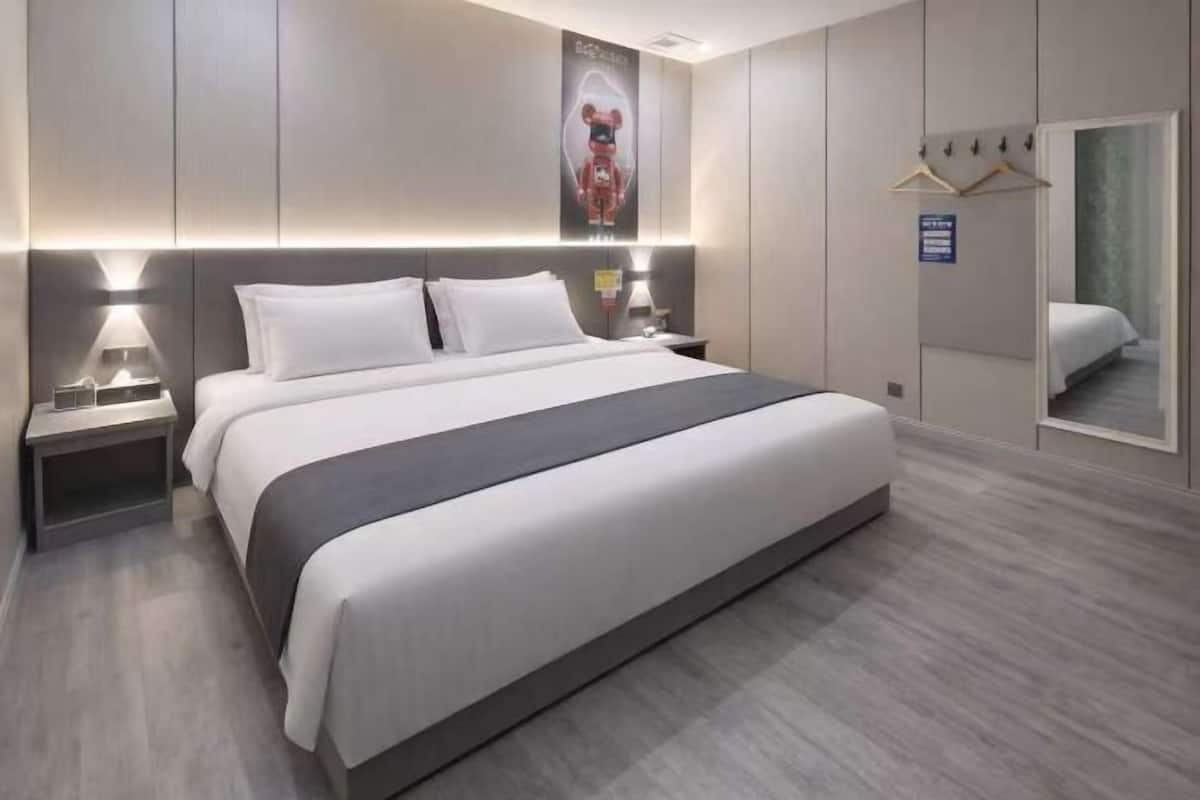 Une chambre d’hôtel avec un grand lit, des tables de chevet, un miroir et une armoire.