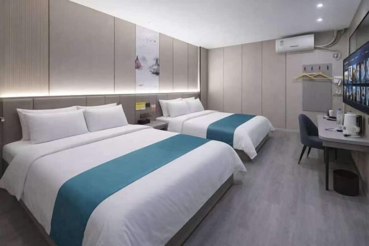 Une chambre d’hôtel avec deux lits, un bureau et une chaise.