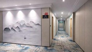 Ein Hotelgang mit einer Wandmalerei von Bergen, einem gemusterten Teppich und einem Schild, das einen Raucherbereich kennzeichnet.