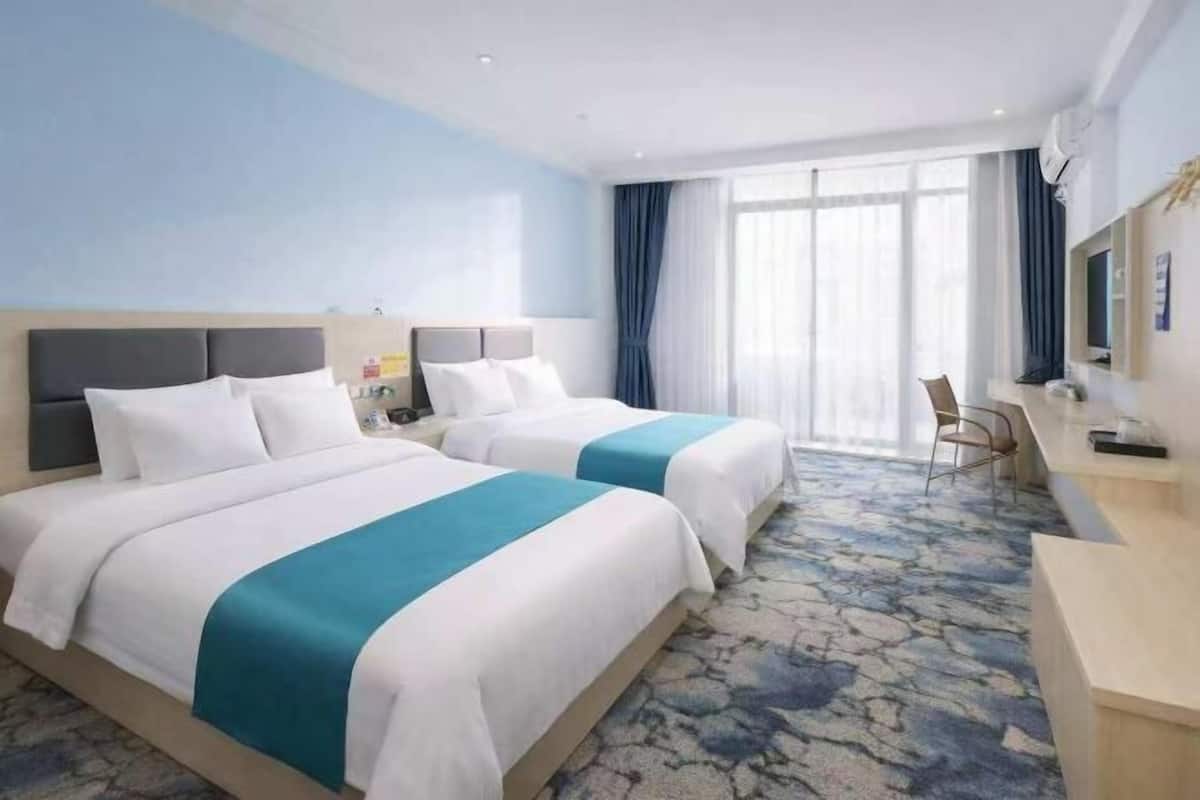 Une chambre d’hôtel avec deux lits, un bureau et une grande fenêtre.