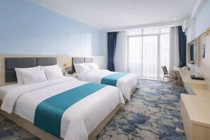 Ein Hotelzimmer mit zwei Betten, einem Schreibtisch und einem großen Fenster.