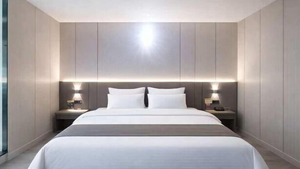 Ein modernes Hotelzimmer mit einem großen Bett, Nachttischlampen und Blick durch ein Fenster.