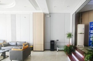 Un vestíbulo moderno con un sofá, un mueble alto, un refrigerador y una planta.