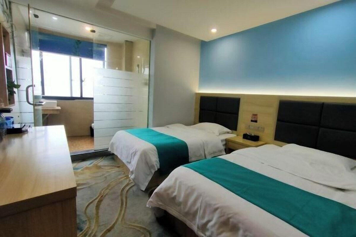 Een hotelkamer met twee bedden, een bureau, een badkamer en uitzicht op de omgeving.