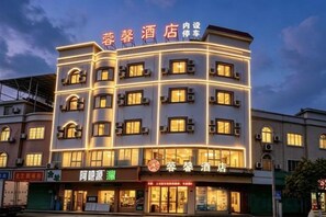 Un hôtel à plusieurs étages, doté d'une enseigne lumineuse, de nombreux balcons et d'un magasin situé au rez-de-chaussée.