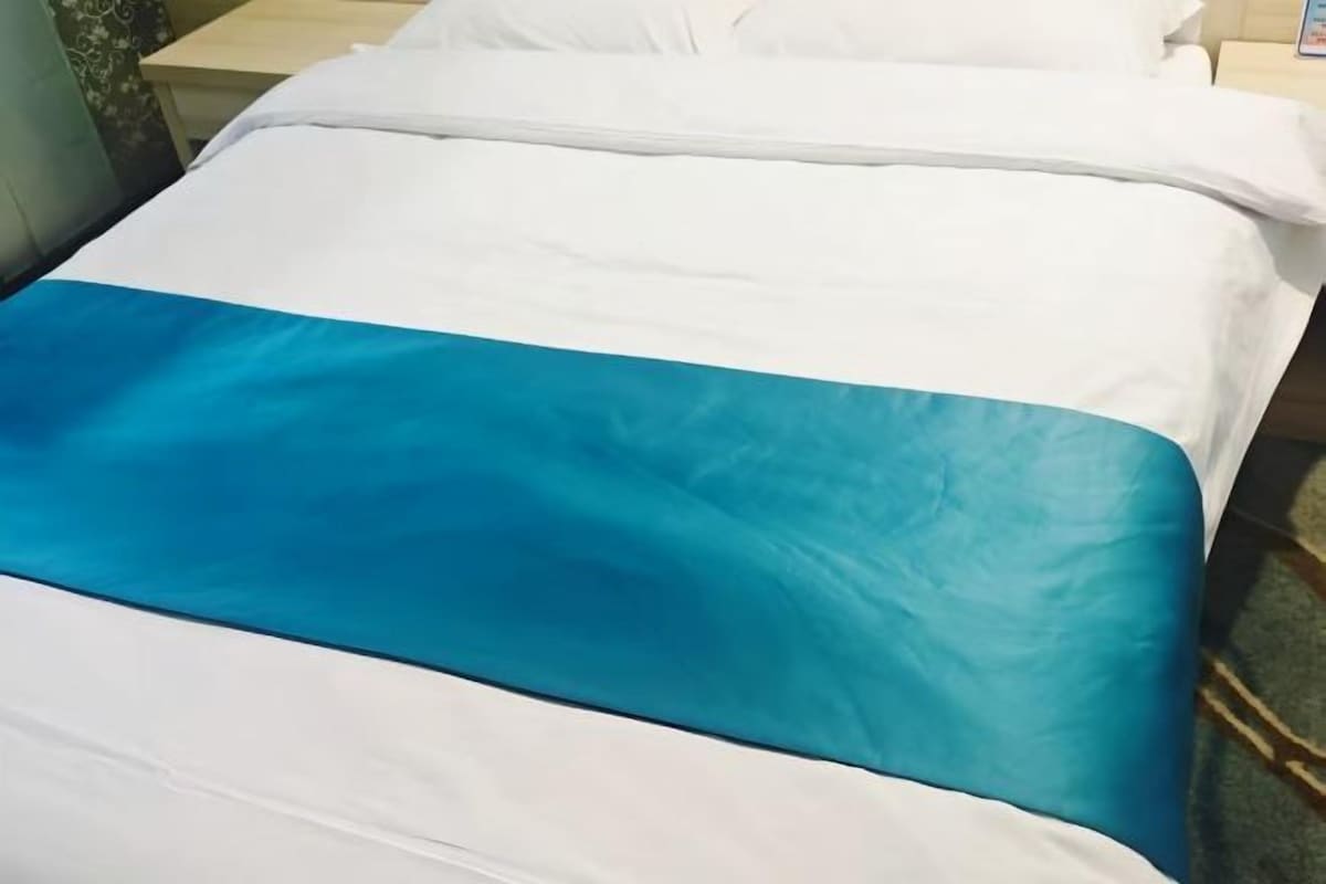 Una cama con una colcha blanca y turquesa.