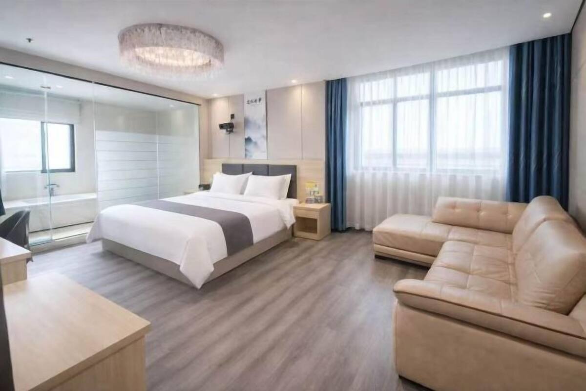 Une chambre d’hôtel moderne équipée d’un lit, d’un bureau, d’un canapé et d’un grand miroir.