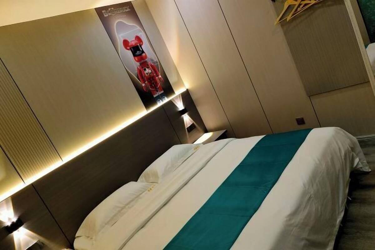 Une chambre d’hôtel avec un lit, une affiche au mur et une table de chevet.