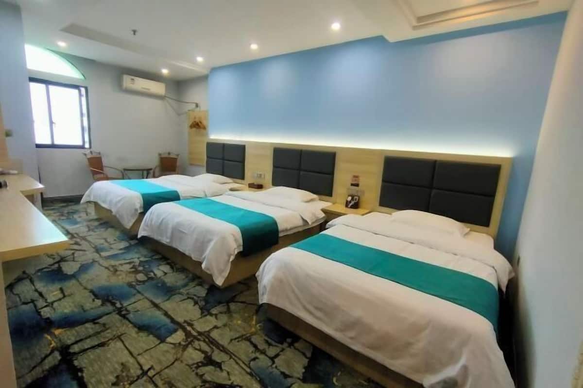 Une chambre d’hôtel avec trois lits, un bureau et une chaise.