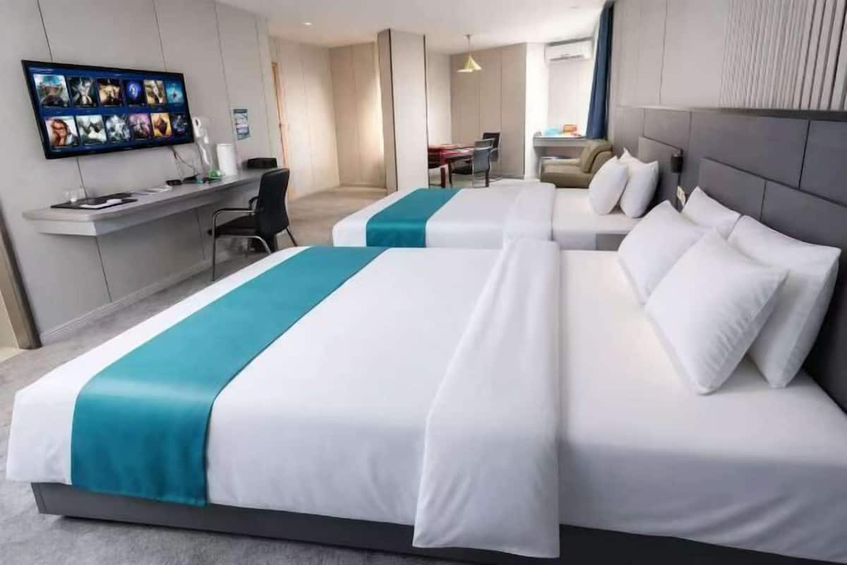 Une chambre d’hôtel avec deux lits, un bureau, une télévision et une vue sur le couloir.