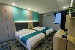 Een hotelkamer met twee bedden, een bureau, een plant en een raam.